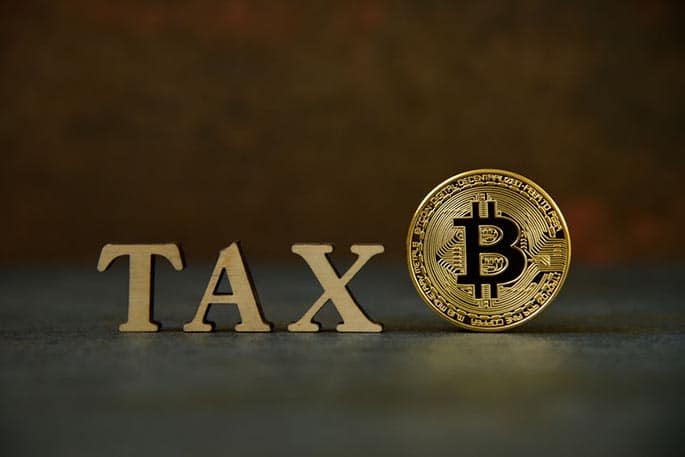 picture of a Bitcoin next to the word tax