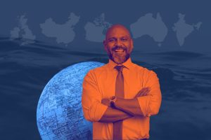 Collage-style photo of a smiling, middle-aged Indian-American man in business attire, positioned in front of a globe. The background shows the outline of countries that commonly trigger FBAR filing requirements: United Kingdom, China, Canada, Australia, and India.