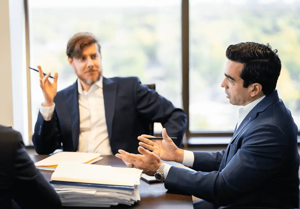 Attorneys Andrew Gordon and Michael Brandwein discussing legal documents in a meeting.